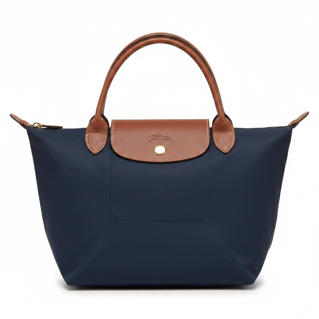 Navy blue handbag with brown leather handles and trim on a white background